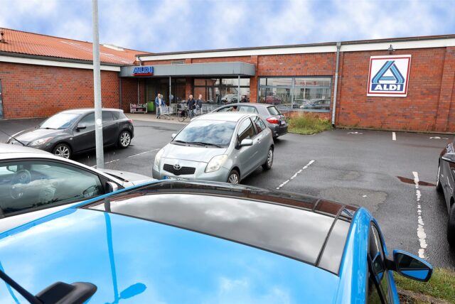 Aldi Lünener Straße, Außenschuss vom Parkplatz aus. Ein paar Autos stehen dort.