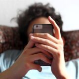 Ein junger Mann blickt auf ein Smartphone.