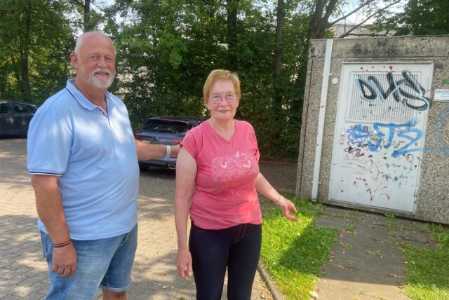 Uwe Görke-Gott von der SPD steht zusammen mit Anwohnerin Angela Stoffers am Parkplatz vor dem Kinderspielplatz an der Friedrich-Hegel-Straße in Schwerte-Holzen.