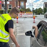 Ein Mann mit einer gelben Weste steht in Unna an der Ecke Beethovenring/Obere Husemannstraße. Ein Autofahrer zeigt ihm einen Ausweis.