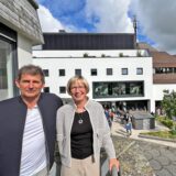 Rainer und Silke Krischer stehen auf einem Balkon in der Unnaer Innenstadt. Im Hintergrund ist die Südfassade des Kaufhauses Schnückel.