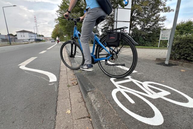 An der Hansastraße in Unna fährt ein Radfahrer vom Geh- und Radweg auf die Fahrbahn (Szene nachgestellt). Mit der Zusammenführung auf dem Bürgersteig widerspreche die Stadt Unna ihren eigenen Beschlüssen, kritisiert der ADFC.