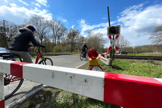 An einem Bahnübergang in Unna umfahren Radfahrer eine Sperre. Sie fahren über die Straße.