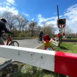 An einem Bahnübergang in Unna umfahren Radfahrer eine Sperre. Sie fahren über die Straße.