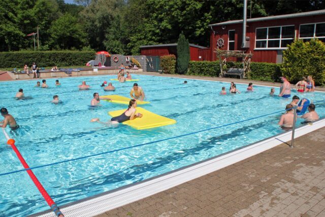 Menschen schwimmen im Wasser in einem Freibad