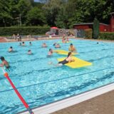 Menschen schwimmen im Wasser in einem Freibad