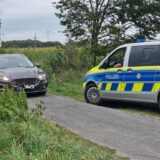 Ein Streifenwagen der Polizei und ein weiteres Auto stehen an einem Feldweg in Gronau-Epe, an dem zwei Leichen gefunden wurden.