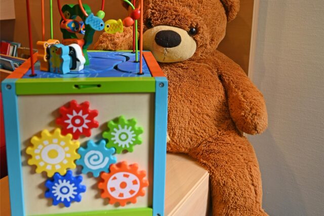 Ein Teddy sitzt neben einer Spielzeugbox.
