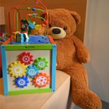 Ein Teddy sitzt neben einer Spielzeugbox.