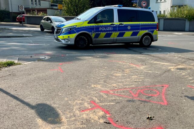 Auf einer Straße in Unna steht ein Polizeifahrzeug. Auf der Fahrbahn sind Markierungen, die einen Unfall dokumentieren.
