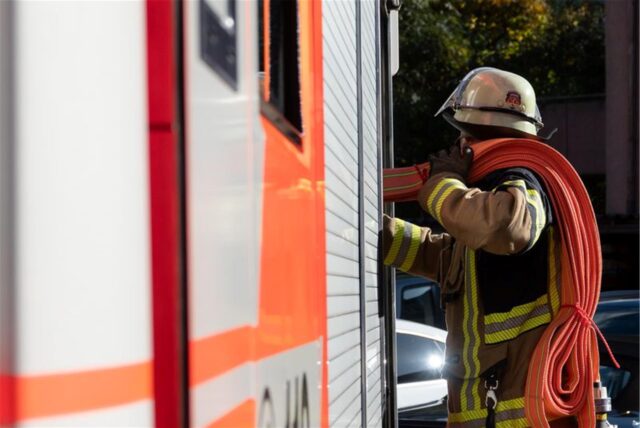 Eine Einsatzkraft der Feuerwehr nimmt während eines Pressetermins einen Schlauch aus einem Einsatzfahrzeug der Feuerwehr Stuttgart (gestellte Szene).