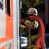 Eine Einsatzkraft der Feuerwehr nimmt während eines Pressetermins einen Schlauch aus einem Einsatzfahrzeug der Feuerwehr Stuttgart (gestellte Szene).