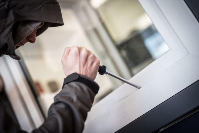 Ein vermummter Mann versucht ein Fenster/Balkon aufzuhebeln.