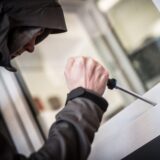 Ein vermummter Mann versucht ein Fenster/Balkon aufzuhebeln.