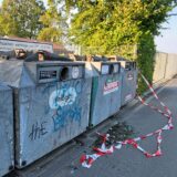 Flatterband und Glasscherben liegen vor einem in Reihe stehenden Altglascontainer.