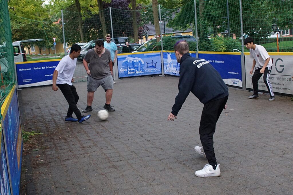 Erwachsene und Jugendliche spielen auf einem mobilen Streetsoccerfeld Fußball Erwachsene und Jugendliche spielen auf einem mobilen Streetsoccerfeld Fußball