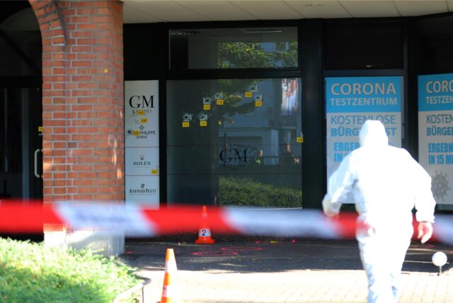 Absperrung der Polizei im Hintergrund das betroffene Geschäft, auf das geschossen wurde.
