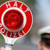 Ein Polizist hält eine Kelle in der Hand, auf der „Halt Polizei“ steht.