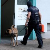 Ein Beamter des Sondereinsatzkommandos betritt mit Hund ein Mehrfamilienhaus.