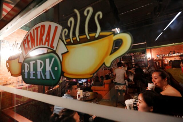 Das Schaufenster des „Central Perk“, dem Café aus der Sitcom „Friends“. Im Café sitzen Personen und trinken aus Bechern.