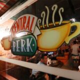 Das Schaufenster des „Central Perk“, dem Café aus der Sitcom „Friends“. Im Café sitzen Personen und trinken aus Bechern.