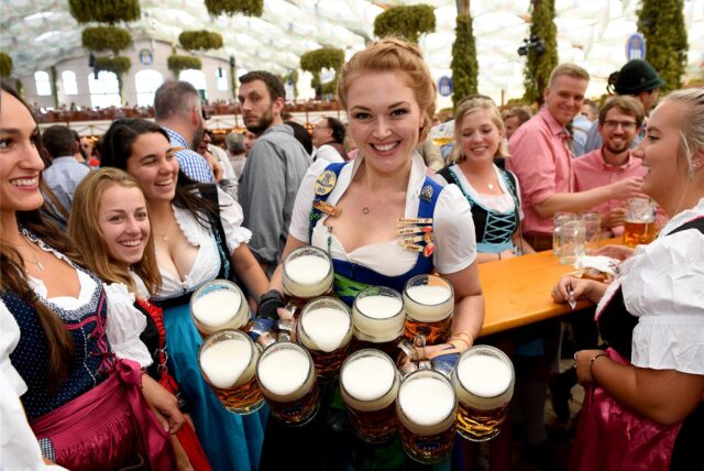 Eine Kellnerin hält mehrere Maßkrüge voller Bier.