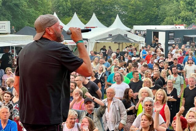 Der Sänger der Coverband „Burning Heart“ singt vor einer Menschenmenge.