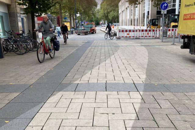 Reinigungsarbeiten in der City haben einen sauberen Streifen Pflaster hinterlassen, der im Kontrast zeigt, wie dreckig das restliche Pflaster in der City ist.