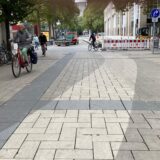 Reinigungsarbeiten in der City haben einen sauberen Streifen Pflaster hinterlassen, der im Kontrast zeigt, wie dreckig das restliche Pflaster in der City ist.