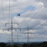 Ein Helikopter fliegt über einer Stromleitung.