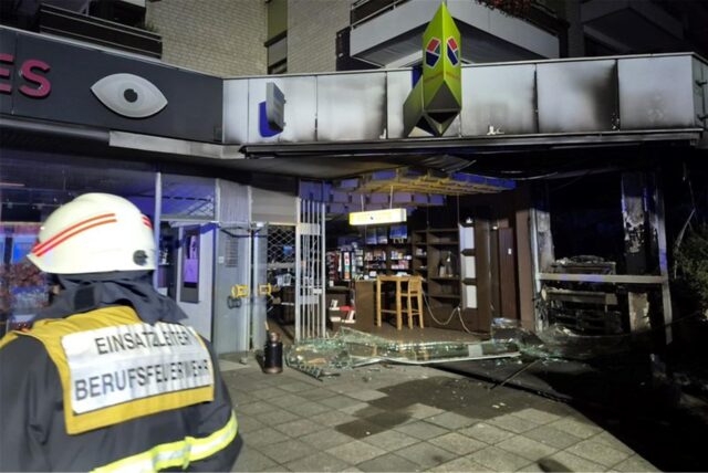 Der Einsatzleiter der Berufsfeuerwehr blickt auf die zerstörte Fassade der Ladenzeile mit Wohnhaus. Nach einer Explosion ist ein Café im Erdgeschoss eines Mehrfamilienhauses in Köln vollständig ausgebrannt.