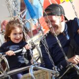 Ein Vater und seine kleine Tochter fahren mit dem Kettenkarussell