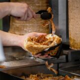 Ein Mitarbeiter einer Dönerbude legt Fleisch in einen Döner