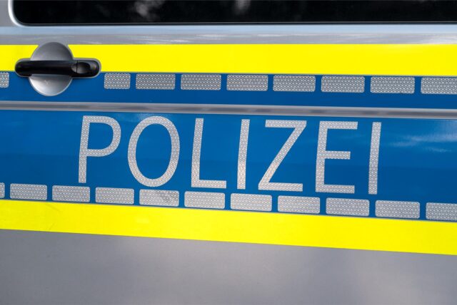 Auf einer Autotür steht in großen Lettern das Wort Polizei