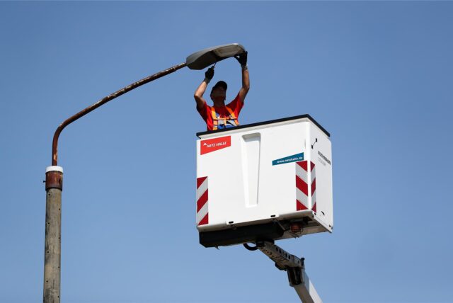 Ein Mann überprüft das Leuchtmittel einer Straßenlaterne