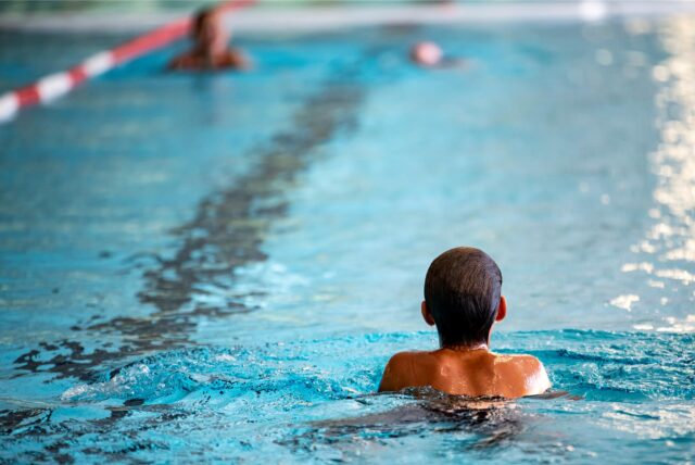 Menschen schwimmen in einem Hallenbad.