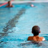 Menschen schwimmen in einem Hallenbad.