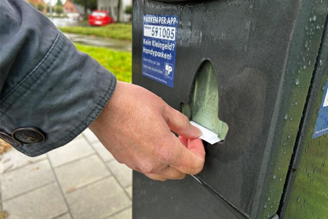Eine Frau zieht einen Parkschein am Automaten.