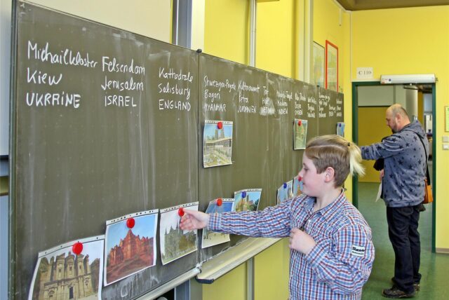 Ein Kind hängt ein Bild an die Tafel eines Klassenraums des Gymnasiums in Selm.