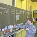 Ein Kind hängt ein Bild an die Tafel eines Klassenraums des Gymnasiums in Selm.