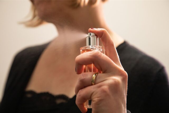 Eine Frau versprüht Parfum aus einem kleinen Flacon