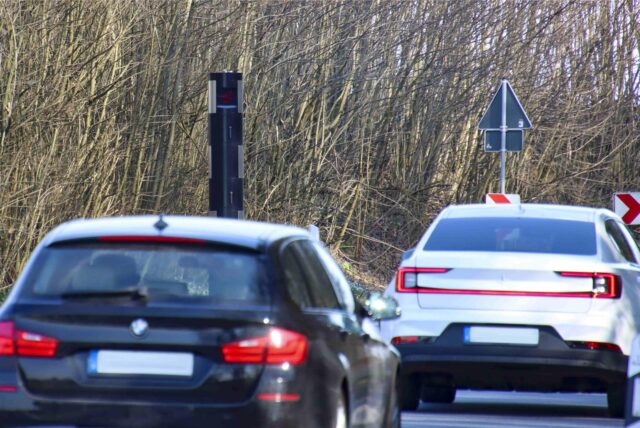 Autos fahren an einem Blitzer vorbei.