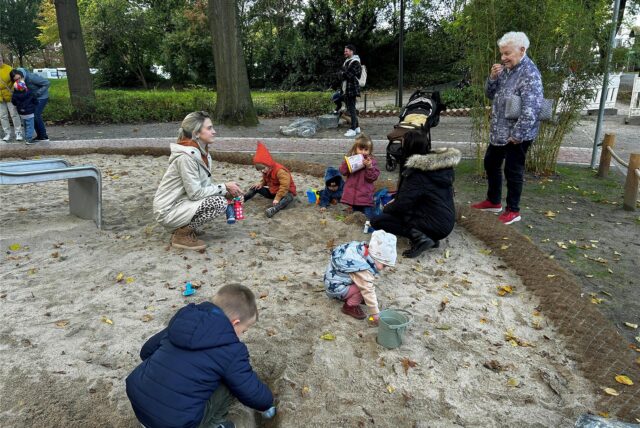 Kinder und ihre Eltern spielen im Sand.