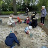Kinder und ihre Eltern spielen im Sand.