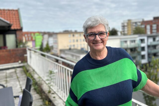 Gabi Kubisch steht auf einem Balkon und lächelt in die Kamera