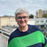 Gabi Kubisch steht auf einem Balkon und lächelt in die Kamera