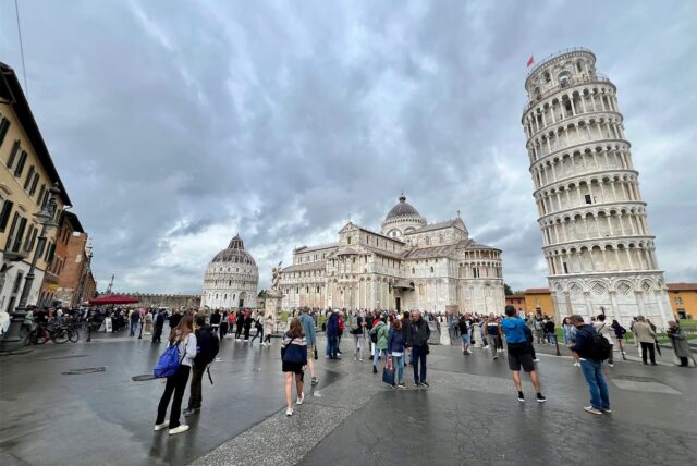 Touristen stehen auf dem Platz vor dem schiefen Turm von Pisa.