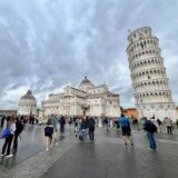 Touristen stehen auf dem Platz vor dem schiefen Turm von Pisa.