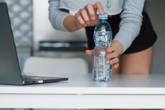 Eine Frau öffnet eine Wasserflasche.