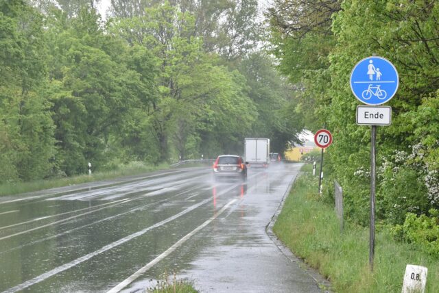 Auf der Industriestraße in Rünthe fahren Autos in Richtung Autobahn.